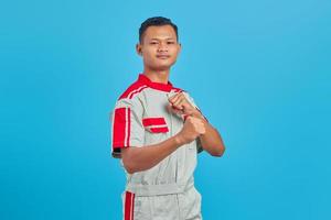 Portrait of angry young Asian mechanic showing boxer gesture over blue background