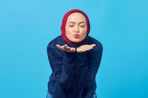 Portrait of charming young Asian woman holding palms sending air kisses in front of camera photo