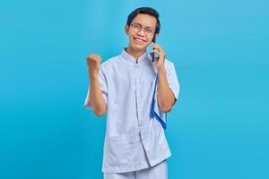 Cheerful handsome male nurse holding clipboard and talking on cell phone on yellow background photo
