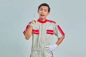 Portrait of excited handsome man wearing mechanical uniform having creative idea and looking at camera over gray background photo