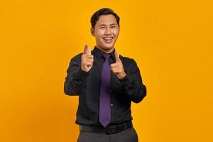Cheerful handsome young businessman pointing at camera on yellow background photo