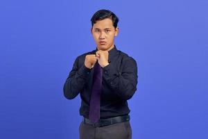 Retrato de hombre asiático joven enojado que muestra el gesto del boxeador sobre fondo amarillo foto