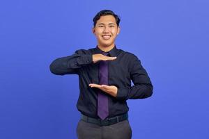 Portrait of cheerful asian man showing product with palm over purple background photo