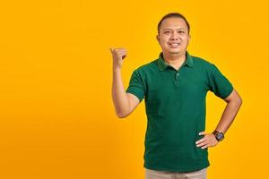 Smiling handsome young man pointing to copy room on yellow background photo