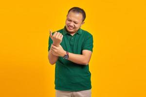 Retrato de un joven asiático que sufre de dolor en las manos y los dedos sobre fondo amarillo