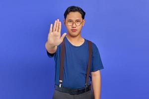 Asian young man doing stop gesture with palm isolated over purple background photo