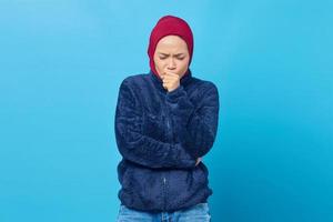 Portrait of beautiful Asian woman feeling unwell and coughing on blue background