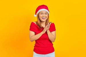 Smiling young woman wearing Christmas hat and applauding after presentation in a conference on yellow background photo