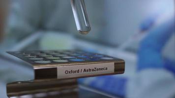 covid 19 oxford astrazeneca-vaccin reageerbuisflesjes worden in een rek geplaatst. afgesloten video