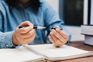 woman holding a pen sitting on a desk writing photo