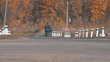 a man on a bicycle crosses a railway crossing against the background of autumn yellowed trees.