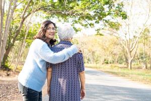 Help and care Asian senior or elderly old lady woman while walking at park in happy fresh holiday. photo