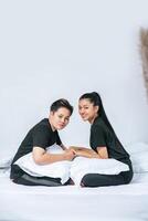 A few women sat on the bed with pillows to support their legs. photo