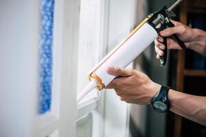 The carpenter holds the glue and attaches to the window. photo