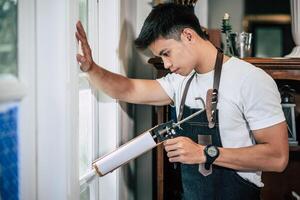 The carpenter holds the glue and attaches to the window. photo