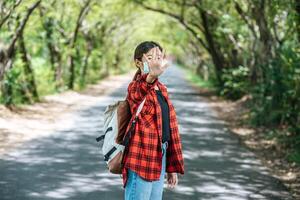 A female tourist carrying a backpack and raising her five fingers to ban on the road. photo