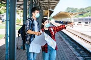 Male and female tourists look at the map beside the railway tracks. photo