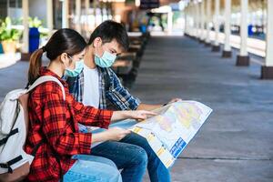 turistas masculinos y femeninos miran el mapa al lado del ferrocarril. foto