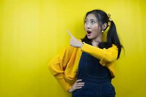 Pretty and cute young woman surprised, shocked, wow expression, hand pointing at empty space, presenting something, promoting product, advertisement, isolated photo