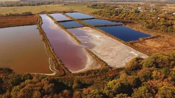 luchtvlucht over waterbezinkingstanks geproduceerd door een drone met vogelperspectief boven een modderig meermoeras in de buurt van een aardappelzetmeelfabriek. op een zonnige avondzonsondergang en ochtendzonsopgang video