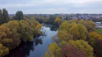 aerial drone flying over a rural river with yellow autumn trees on a warm evening. video