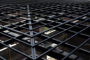 Low angle view of metal structure of roof at the construction site with bricklayers wall below photo