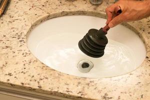 Man Using a Plunger to unstop his bathroom sink