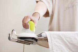 Female hand ironing cotton clothes in home. photo