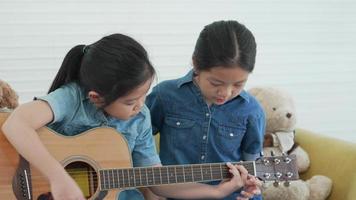 hermana mayor enseñando a la hermana menor a tocar la guitarra en casa video