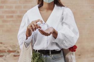 front view woman with face mask using hand sanitizer