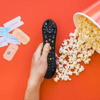 hand holding remote control popcorn movie tickets photo