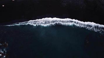 video drone delle onde nella spiaggia di sabbia nera.