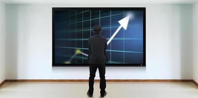 Successful businessman standing in front of TV screen photo