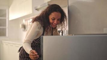 Latijnse vrouw open koelkast of koelkast in keuken video