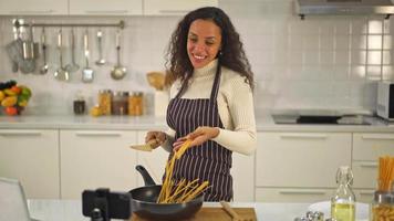 Latin woman shooting video and cooking at the kitchen for share on blog