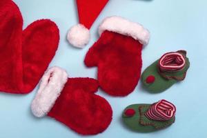 Santa Claus hats, mittens and socks mockup on blue background. Christmas flat mockup, close up top view photo