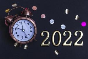 Alarm clock with gold numbers on a black background. Minimal concept of the new year 2022 photo