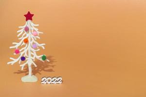 Christmas card. Against the background of Christmas lights, a white Christmas tree in multi-colored fur toys with the numbers 2022. copy space photo