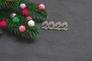 Christmas card. On a black background, a flat New Year's layout of a close-up of a Christmas tree branch, multi-colored fur toys with the numbers photo