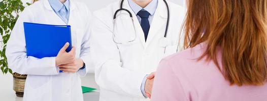 Doctor is talking with woman patient and sitting in medical office photo