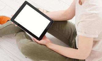 teen woman girl using a tablet pc sitting on the floor in a living room , touching blank screen photo