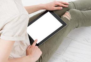 teen woman girl using a tablet pc sitting on the floor in a living room , touching blank screen photo