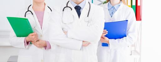 doctor posing in office with medical staff, he is wearing a stethoscope photo