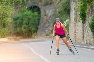 Beautiful sporty blonde girl with Rollerblade and climbing stick photo