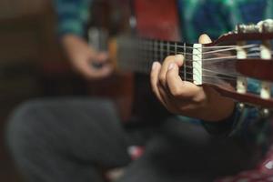 A child plays the classical guitar. detail on the fingers of the left mono photo