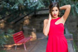 Beautiful girl with red dress holding her hair with her hands photo