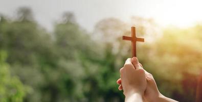 girl holding a cross to pray thank god Praise the Lord with outdoor background, pray, easter and good holidays concept photo