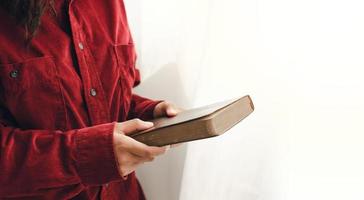 A young woman standing and praying on the Bible, copy space. Beside the mirrored window photo