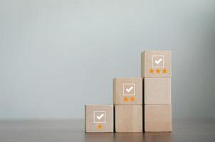 wooden block in review concept Survey and Assessment Concept The wooden blocks are arranged in a pyramid. cube with check mark icon on wooden block Gray background with copy space photo