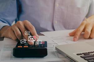 A business man reading an outstanding letter from a taxpayer along with writing down the calculation of the annual tax calculator to prevent and block spam emails from the internet photo